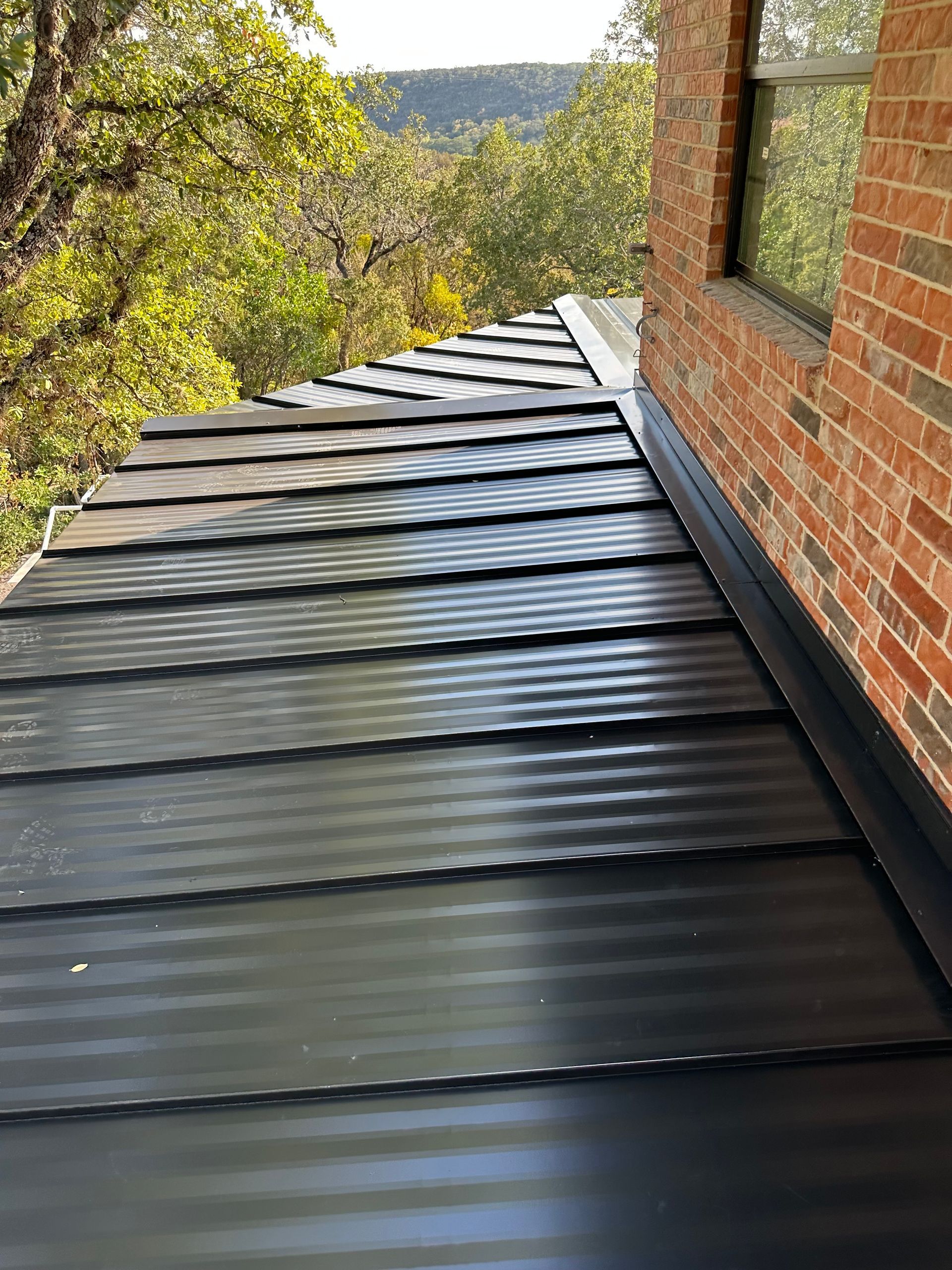 A black metal roof is sitting on top of a brick building.