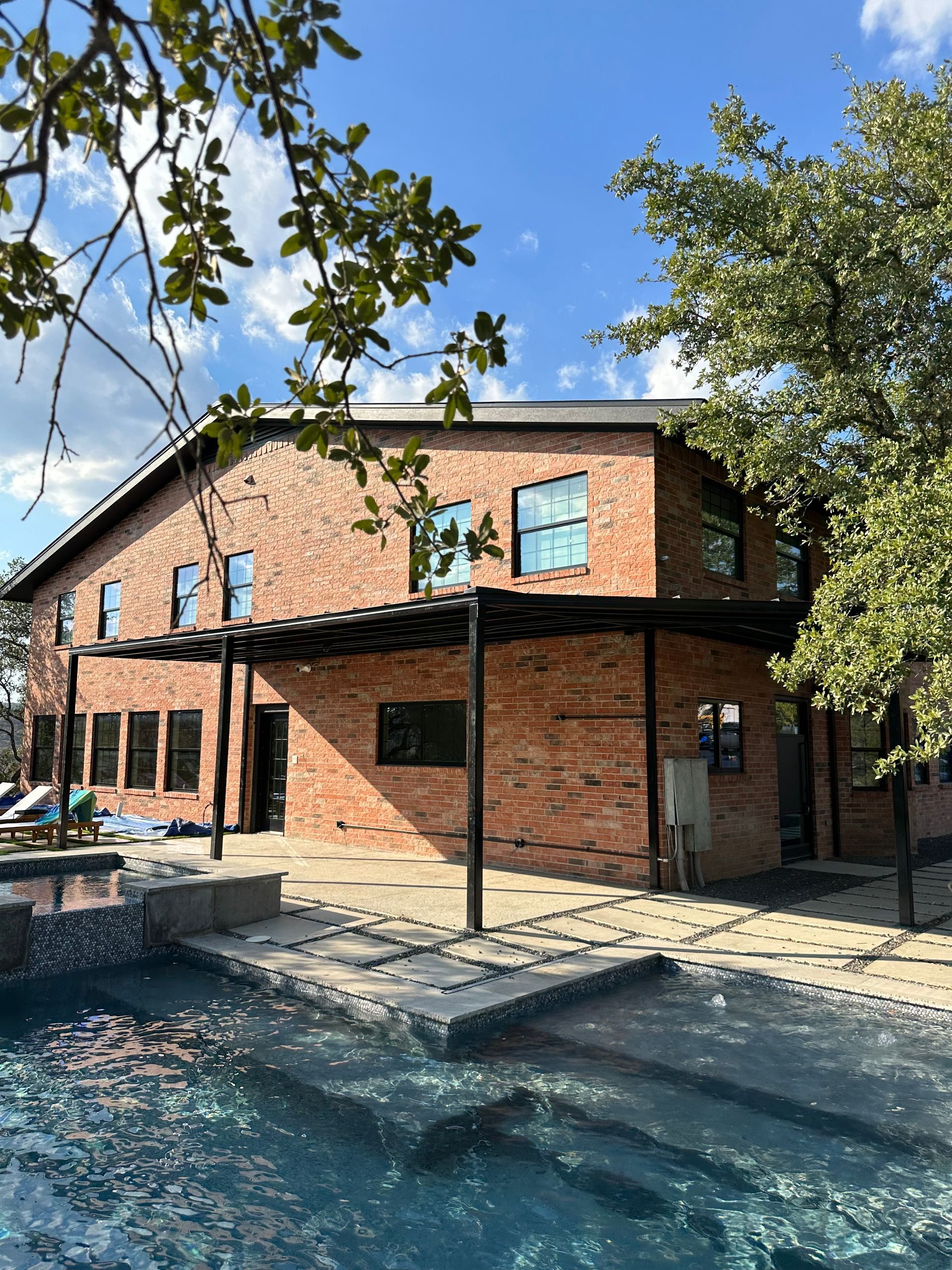 A large brick house with a swimming pool in front of it.