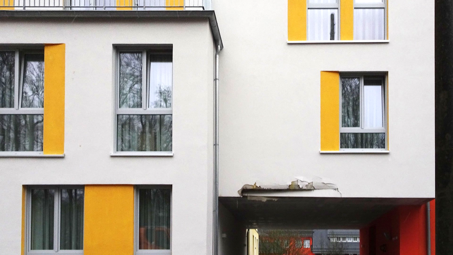 Ein weißes Gebäude mit gelben Fenstern und einer roten Tür