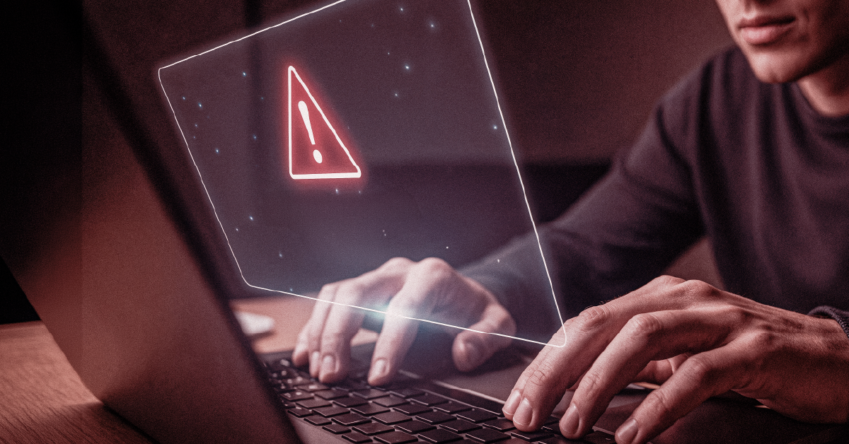 Pessoa digitando em notebook com alerta vermelho de erro ou ameaça digital na tela holográfica.