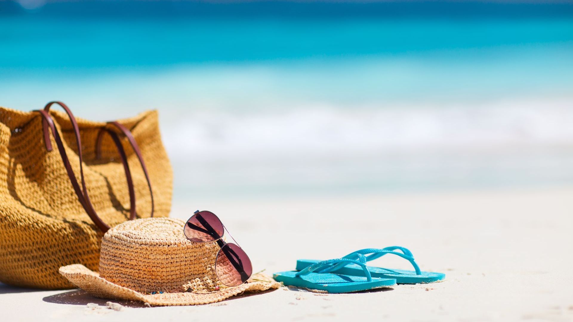 bag, beach hat and slipper on the beach sand