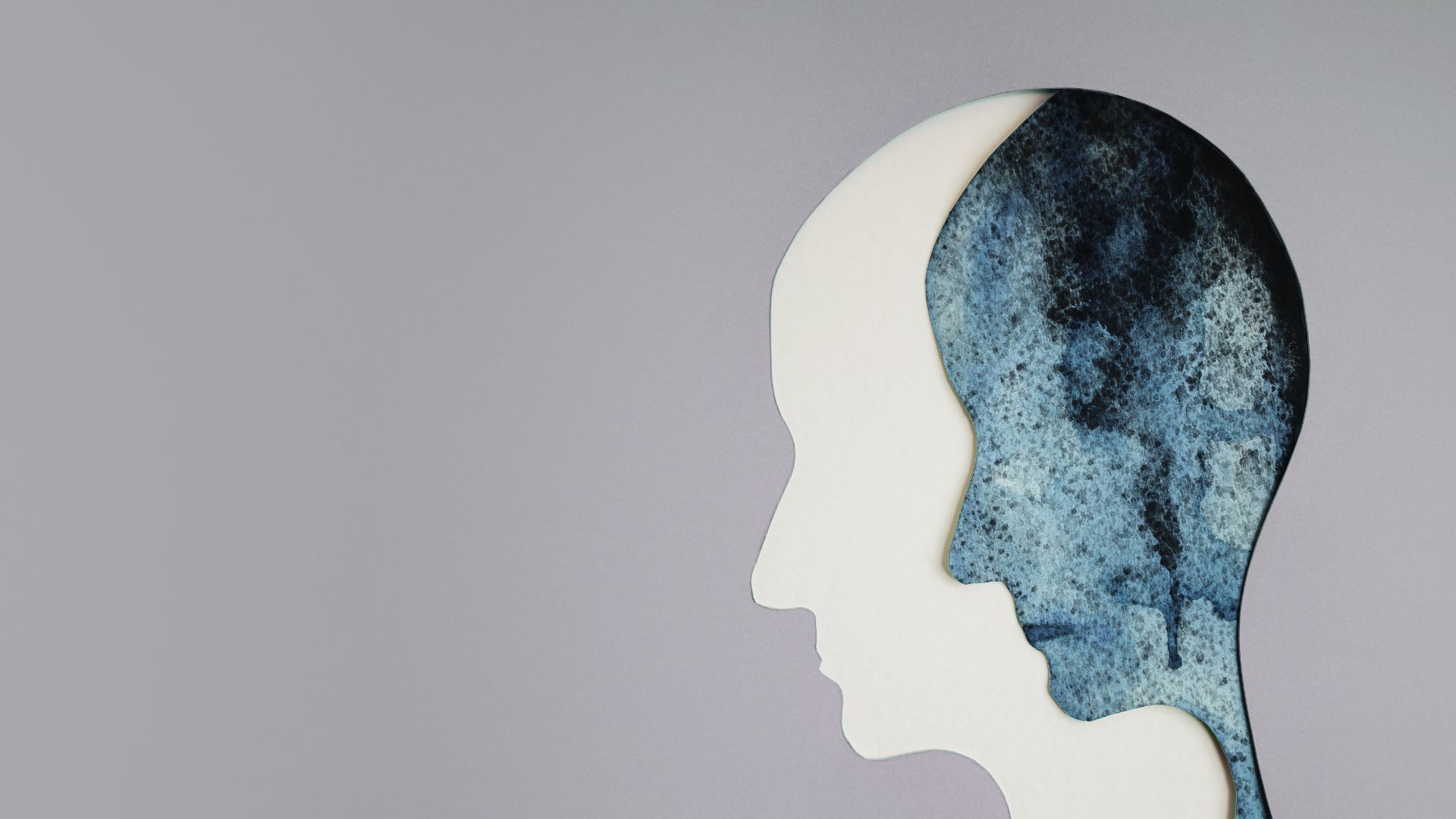 Sagoma di una testa con all'interno un disegno ad acquerello blu, che suggerisce pensieri o emozioni.
