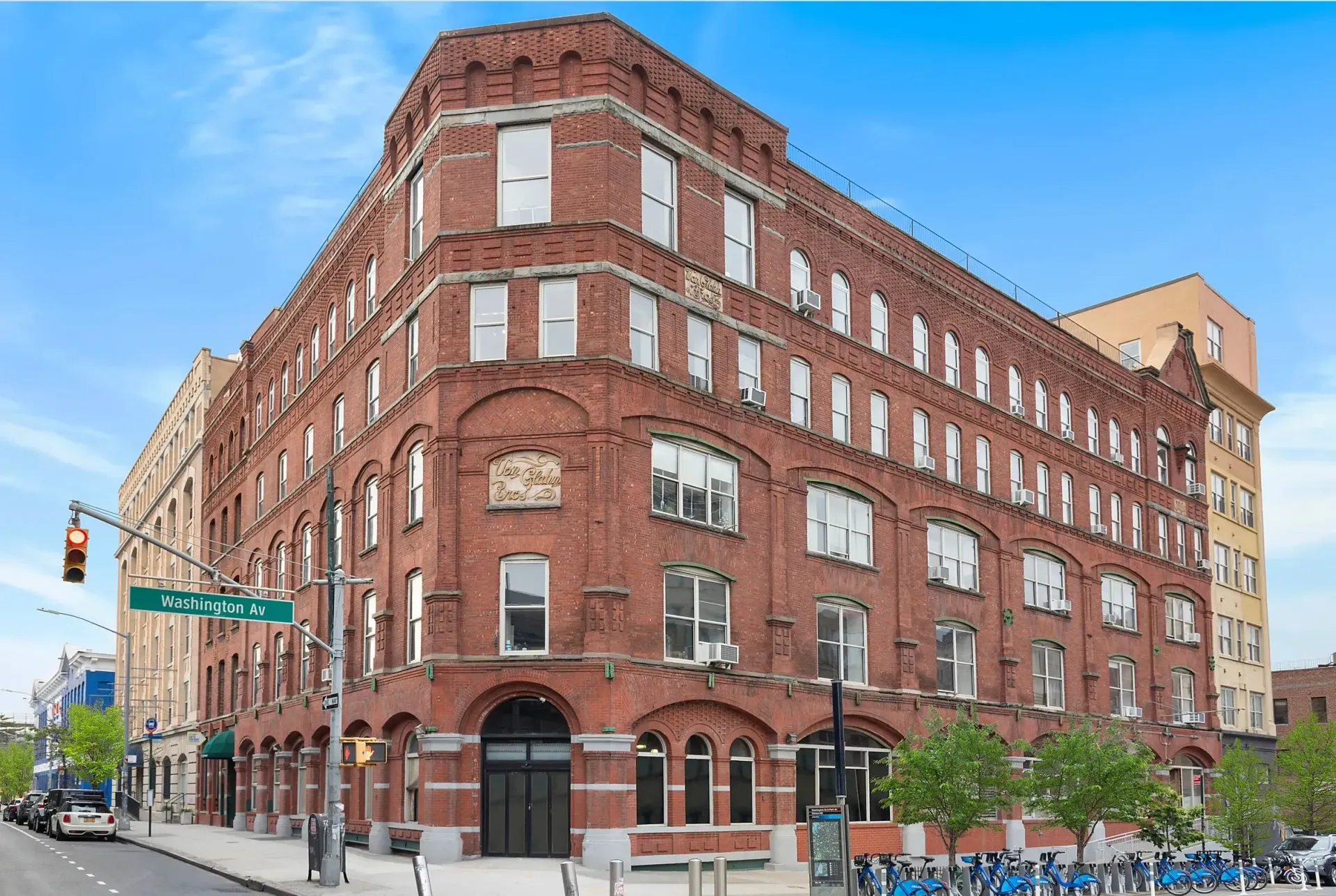 A large brick building is on the corner of a city street.