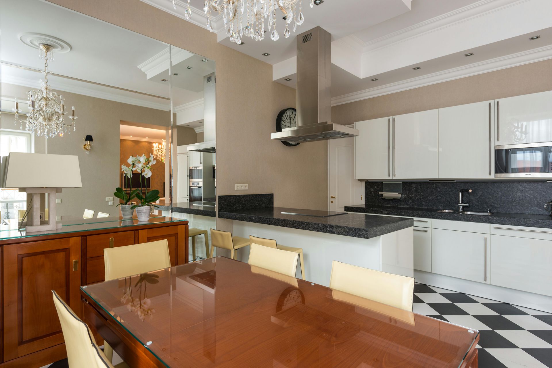 Elegant kitchen with white cabinets, dark countertops, and checkered floor. Dining table with chairs visible.