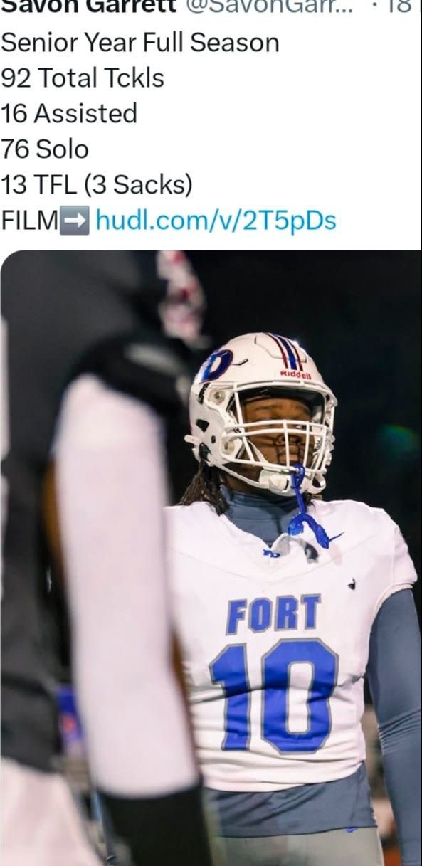 Football player in white and blue Fort jersey and helmet, standing on the field