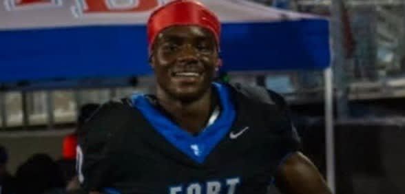 Smiling athlete in black jersey with blue trim and red headband