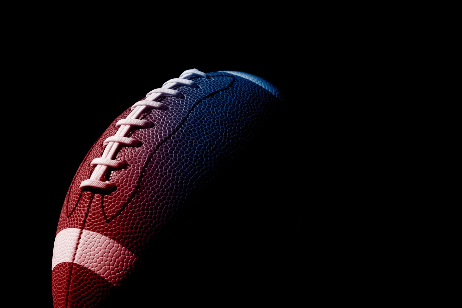Close-up of a red and blue American football on a black background