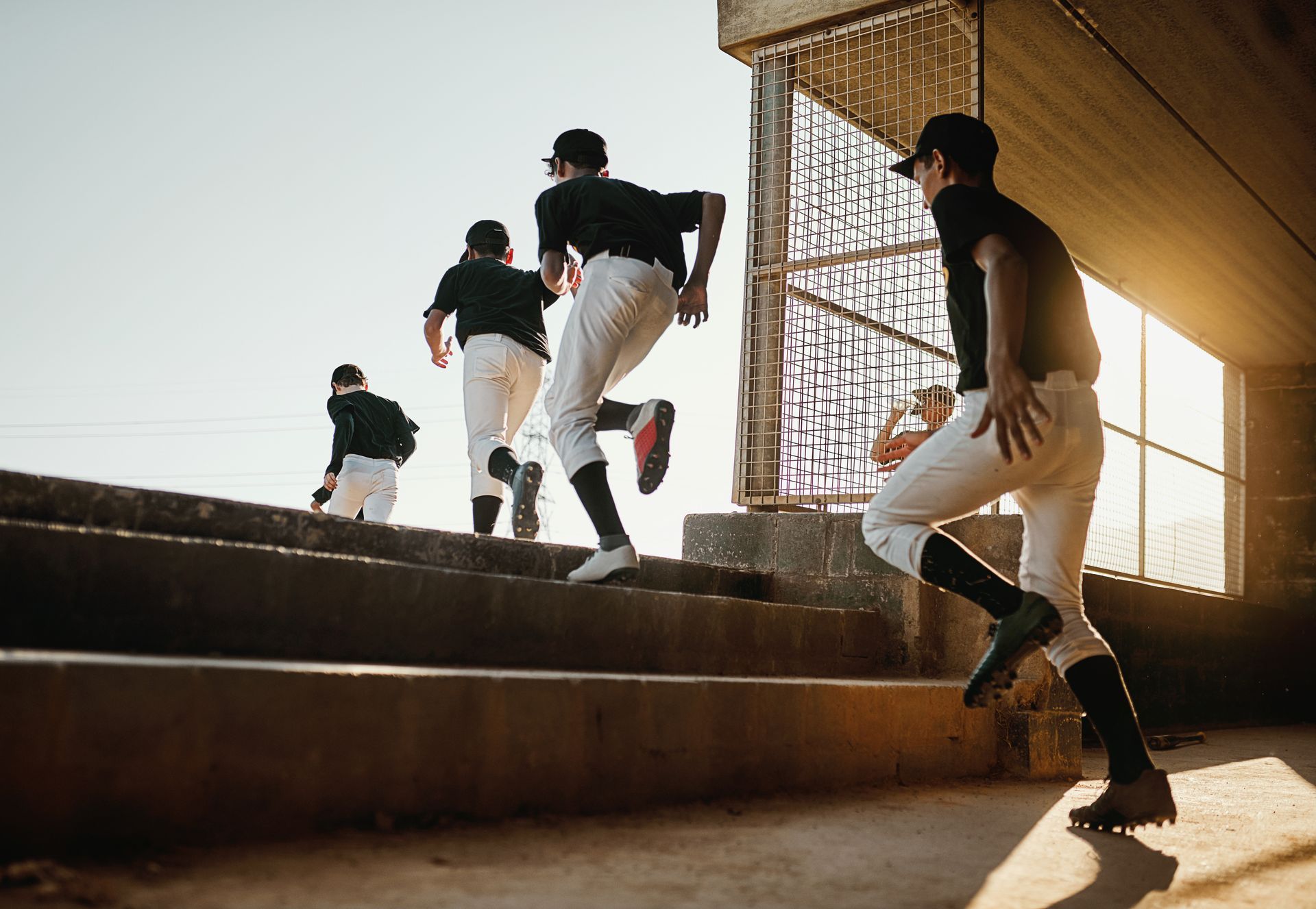 Three people running up sunlit concrete stairs in an urban setting