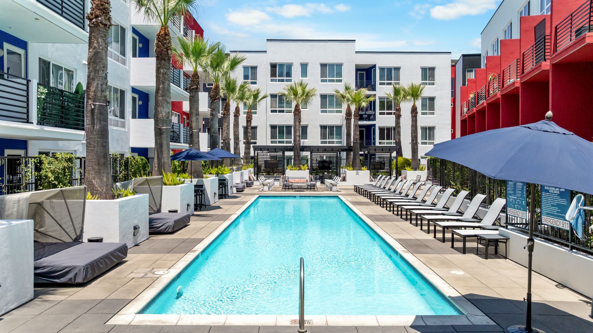 a swimming pool in a building courtyard surrounded by palm trees