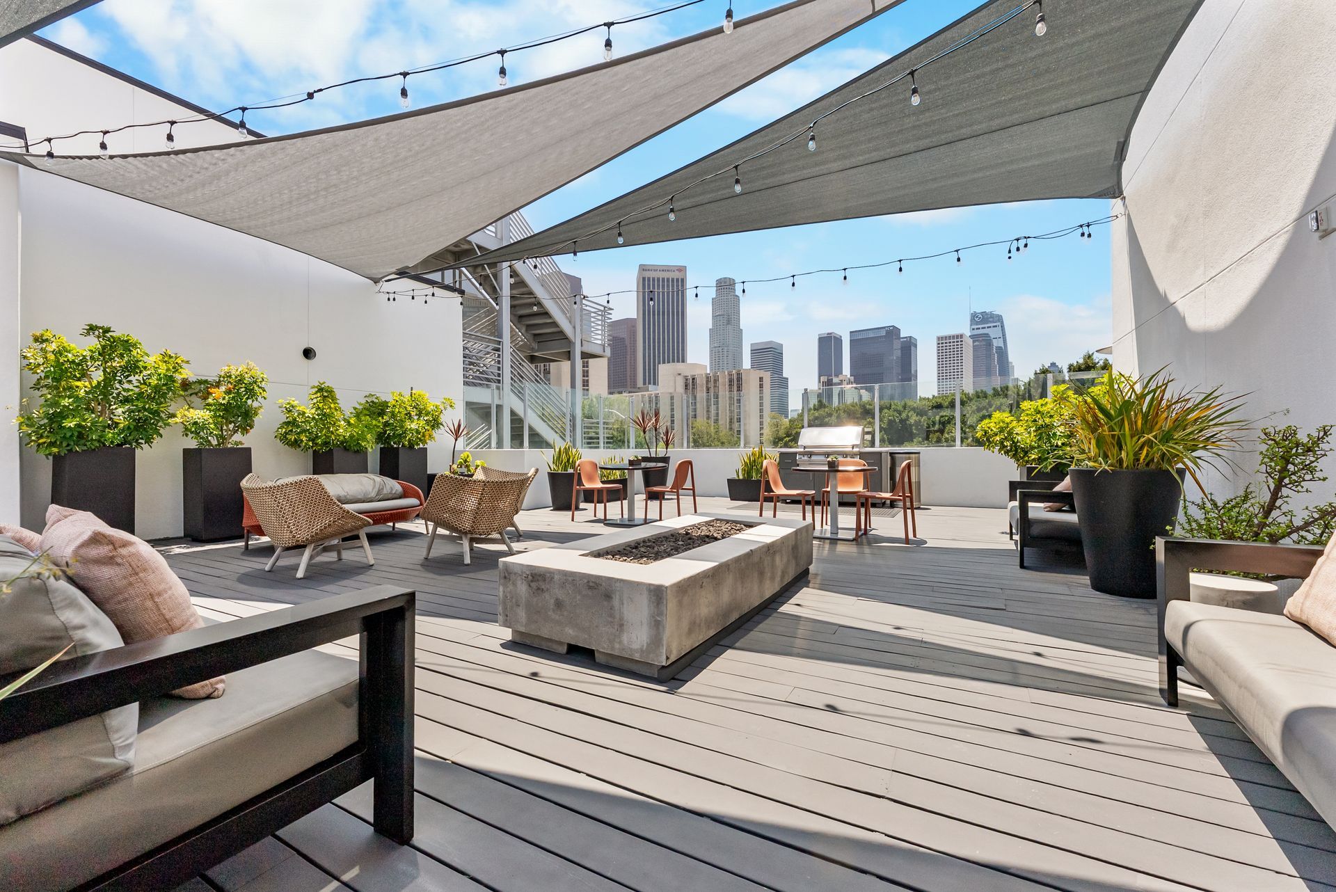 A fire pit and chairs under a canopy with sky scrapers in the background