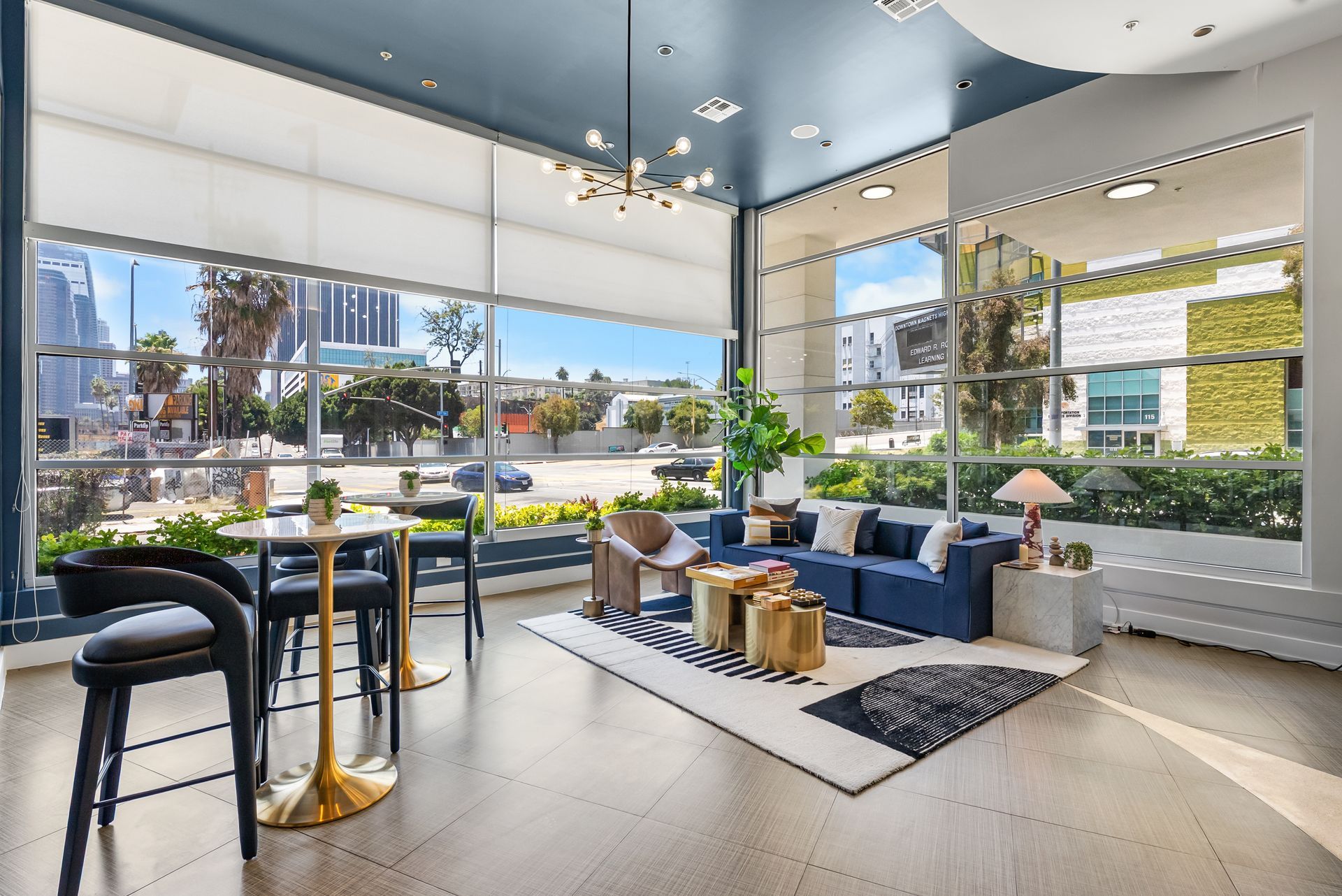 a seating area with end tables next to large windows