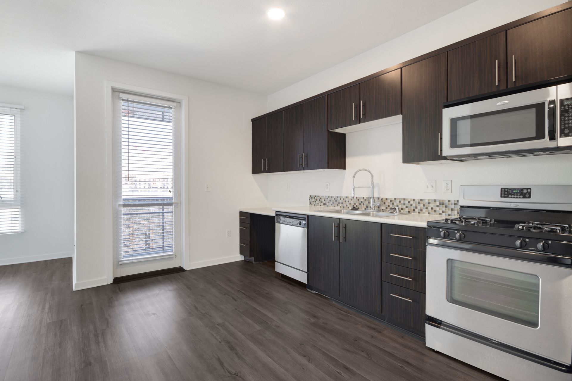an empty kitchen with a store, microwave, counters, and dishwasher