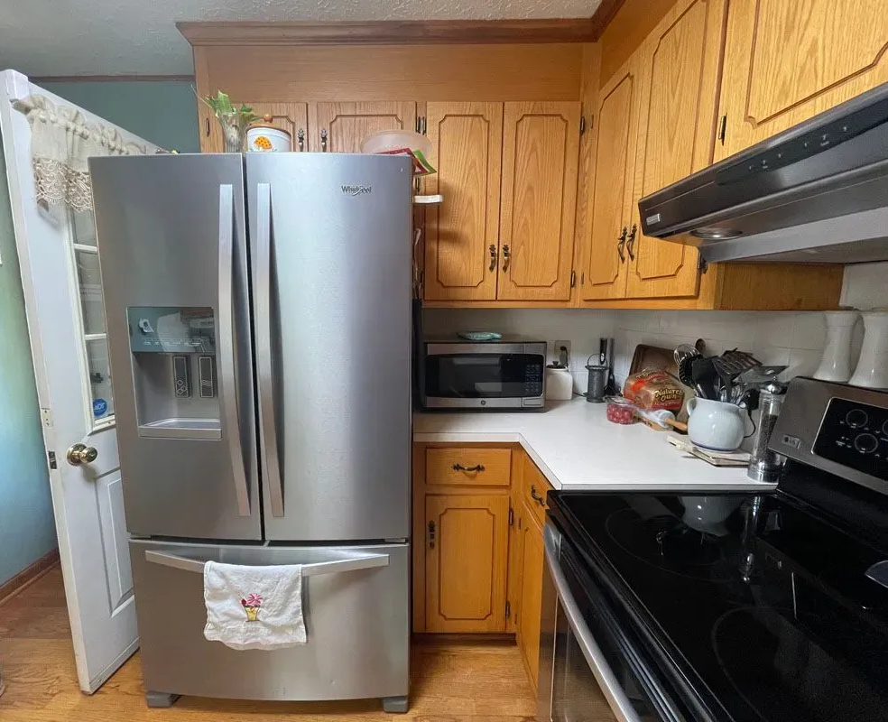A kitchen with a stainless steel refrigerator , stove , and microwave.