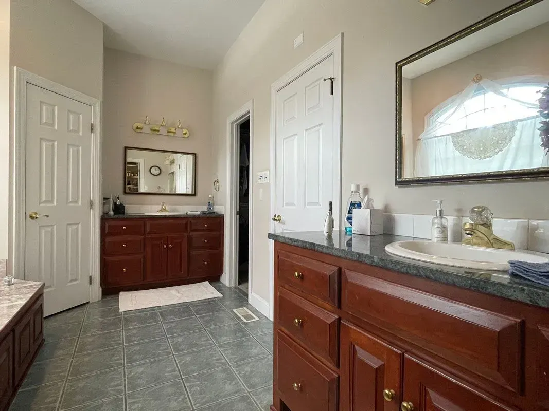 A bathroom with a sink , mirror , cabinets and drawers.