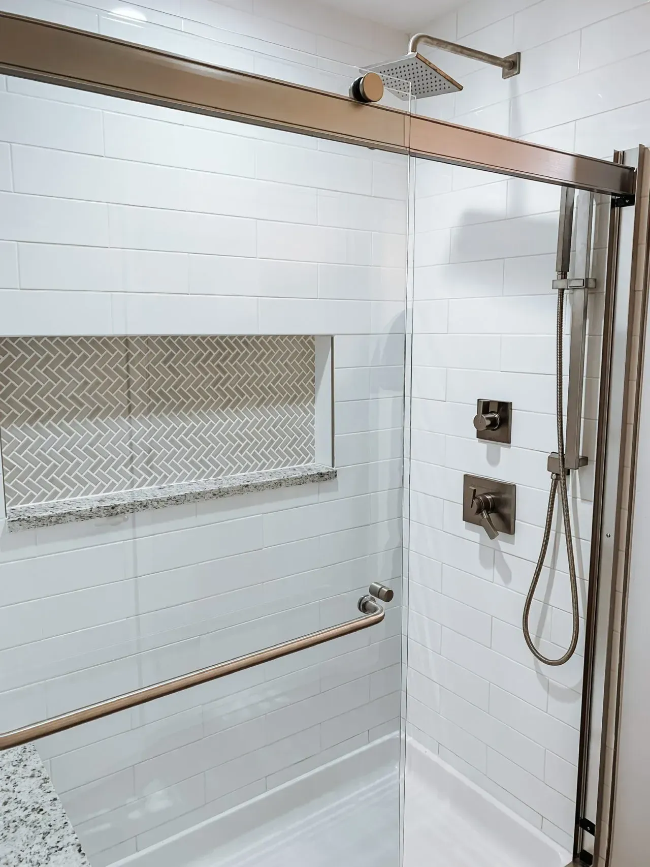 A shower with a sliding glass door and a shower head.