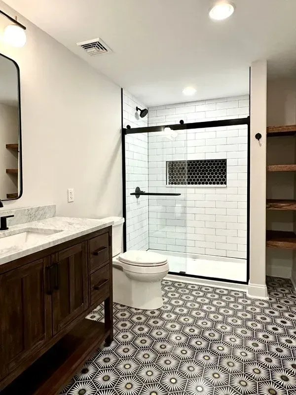 A bathroom with a toilet , sink , mirror and shower.