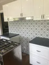 White Kitchen Cabinets and Patterned Backsplash Above the Stove — Alcando Renovations and Maintenance In Bobin, NSW