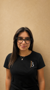 Woman wearing glasses and a black T-shirt stands against a beige wall.