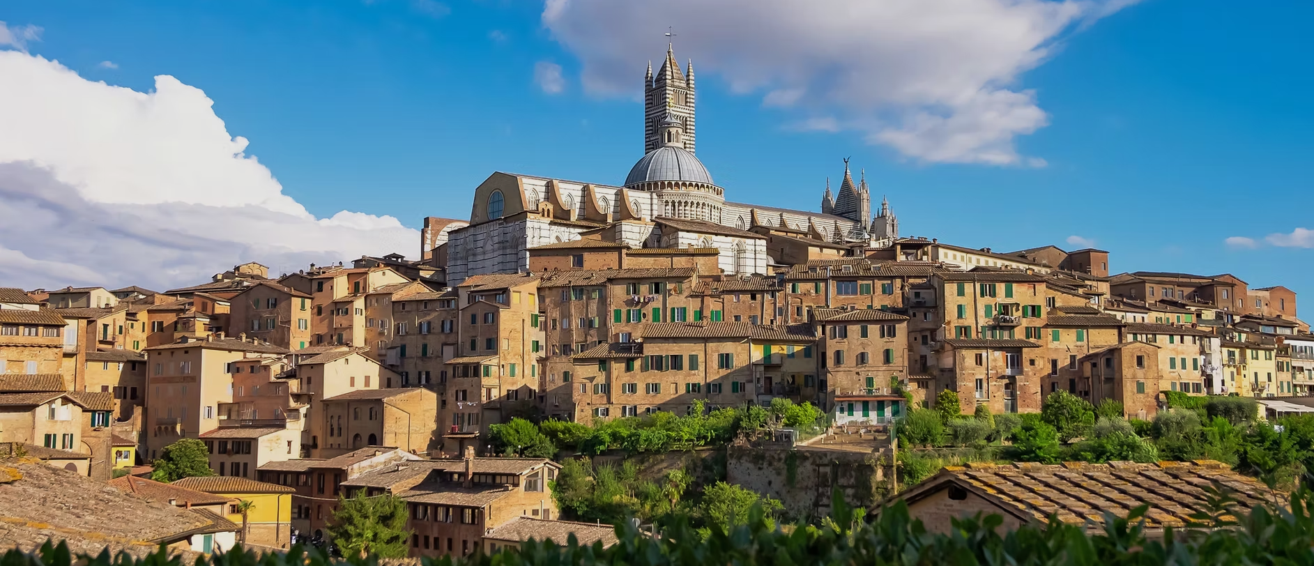 Hilltop stone village with a cathedral, under a blue sky with clouds