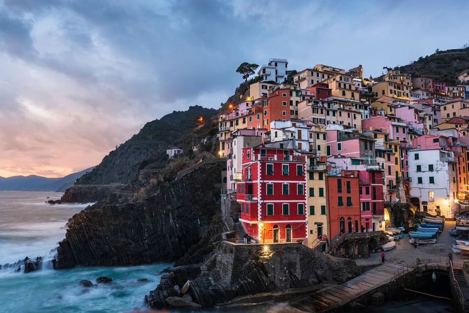 Colorful cliffside village with pastel buildings overlooking a rocky seaside cove at sunset