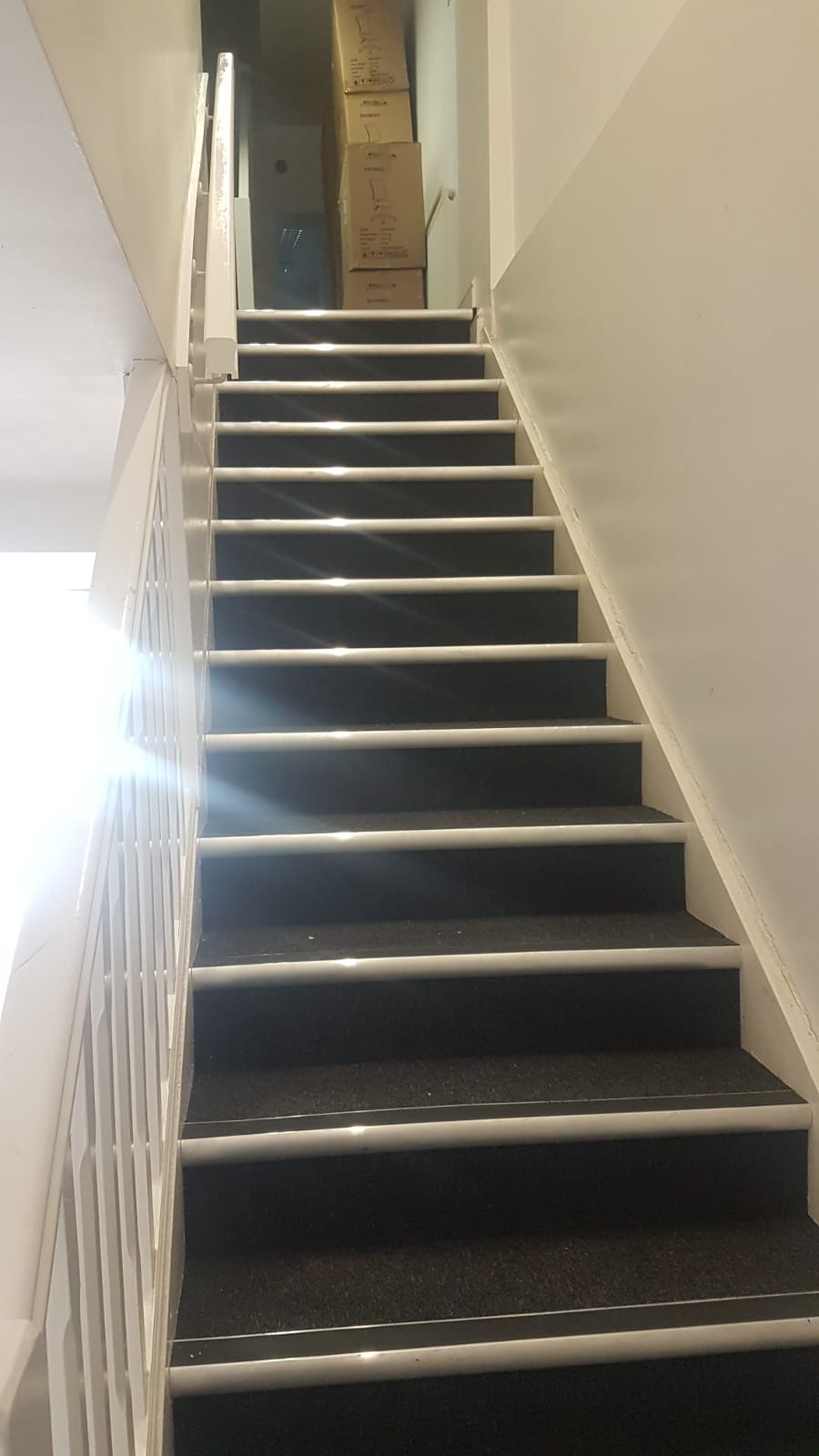 A set of stairs leading up to a room with boxes on the wall.