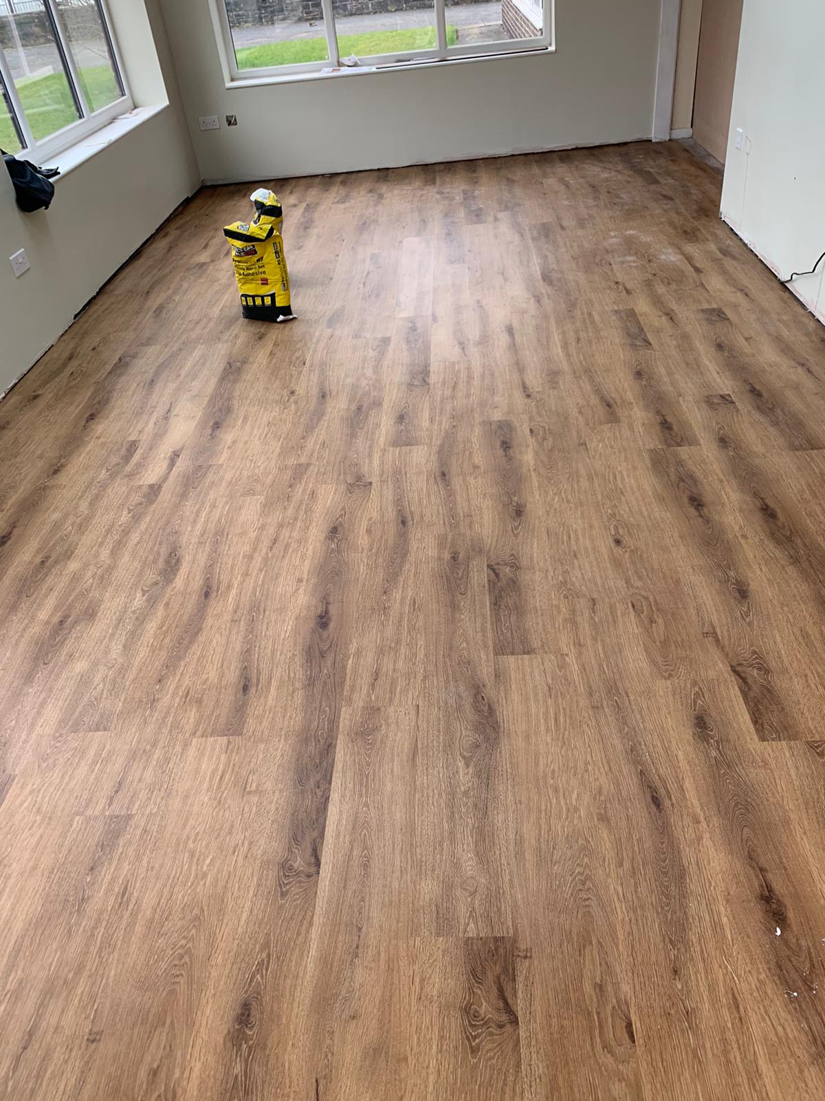 A person is standing on a wooden floor in a room.
