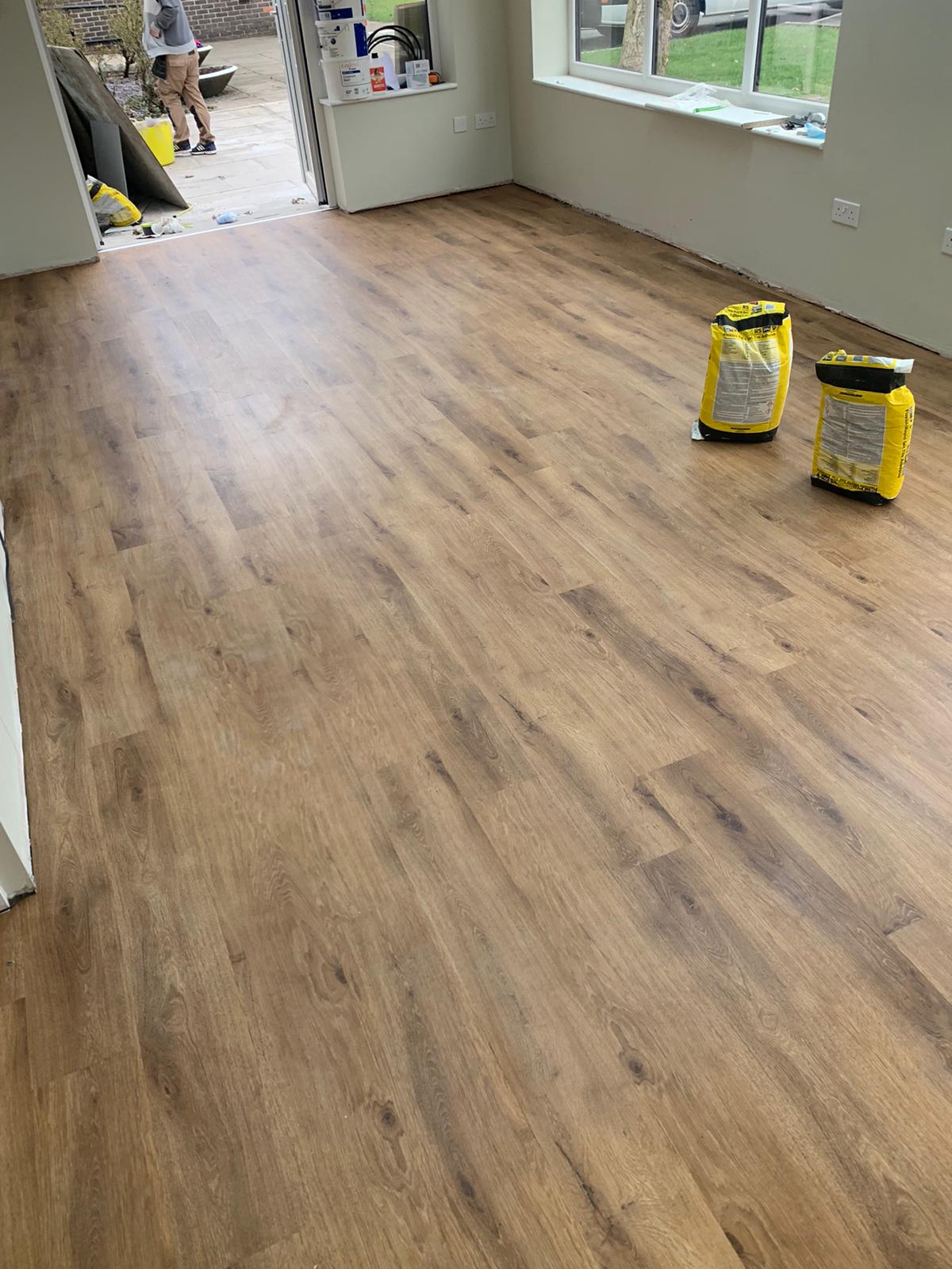 A room with a wooden floor and yellow bags on the floor.