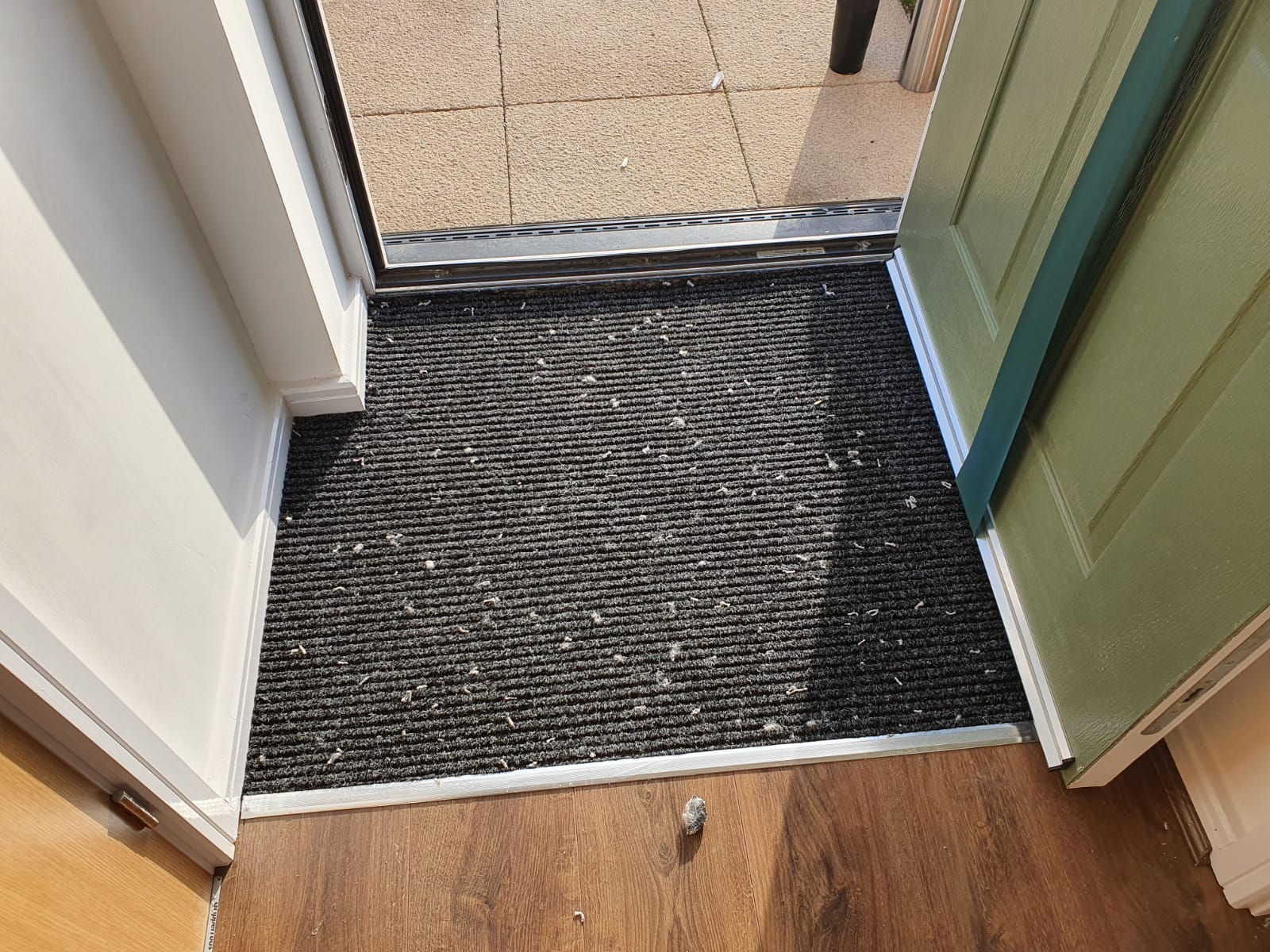 A black door mat is on the floor next to a door.