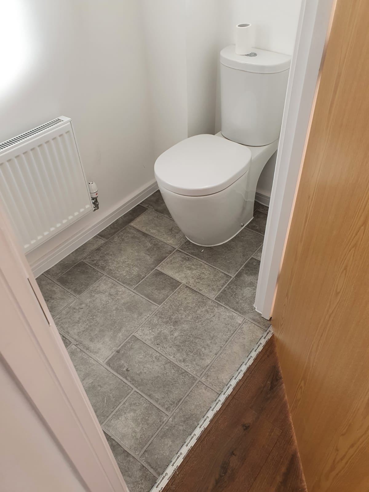 A toilet is sitting in a small bathroom next to a door.