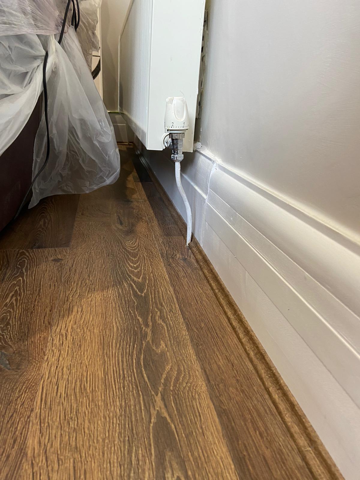 A close up of a wooden floor next to a radiator in a room.