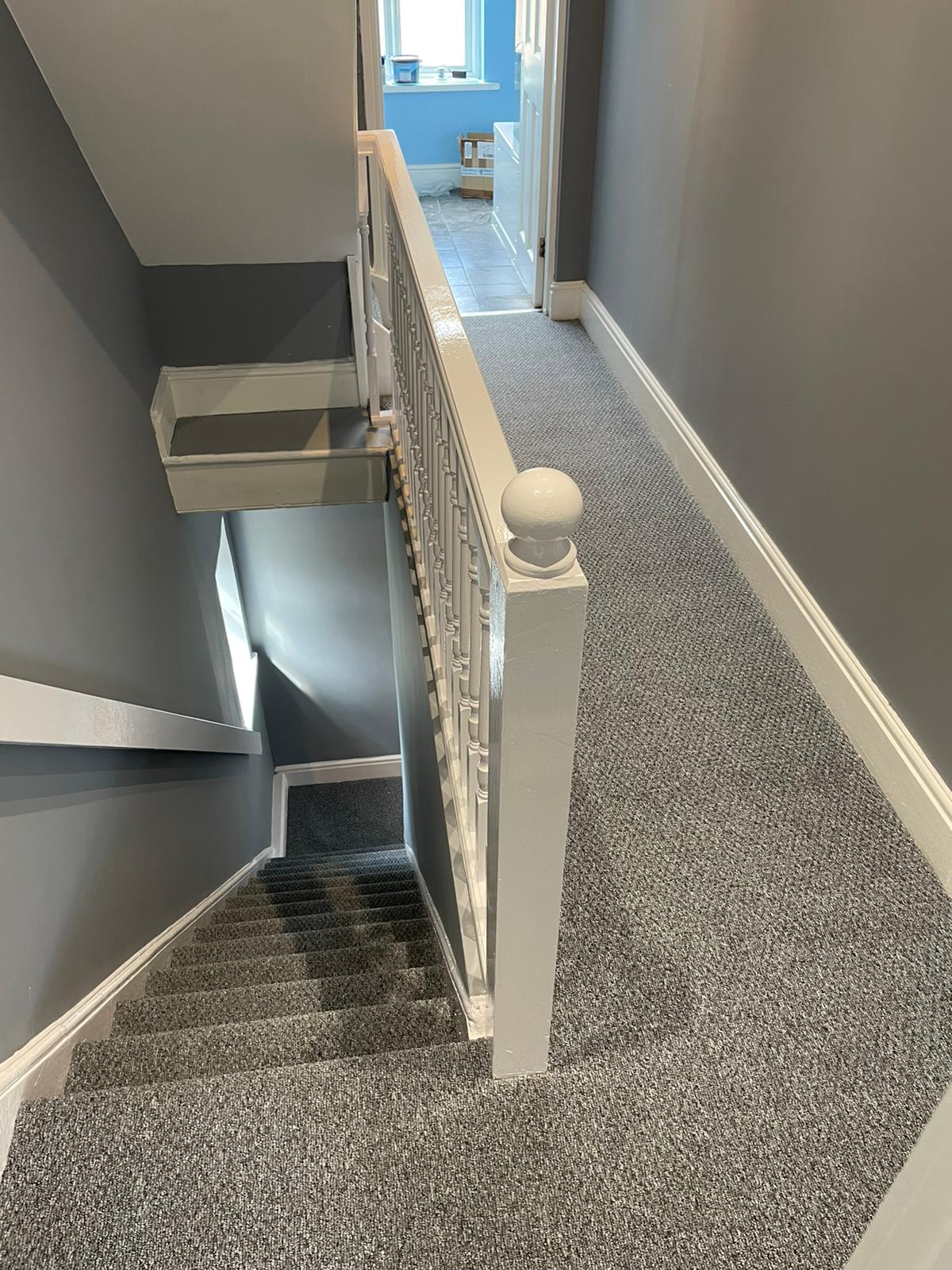 A staircase with a white railing and a gray carpet.