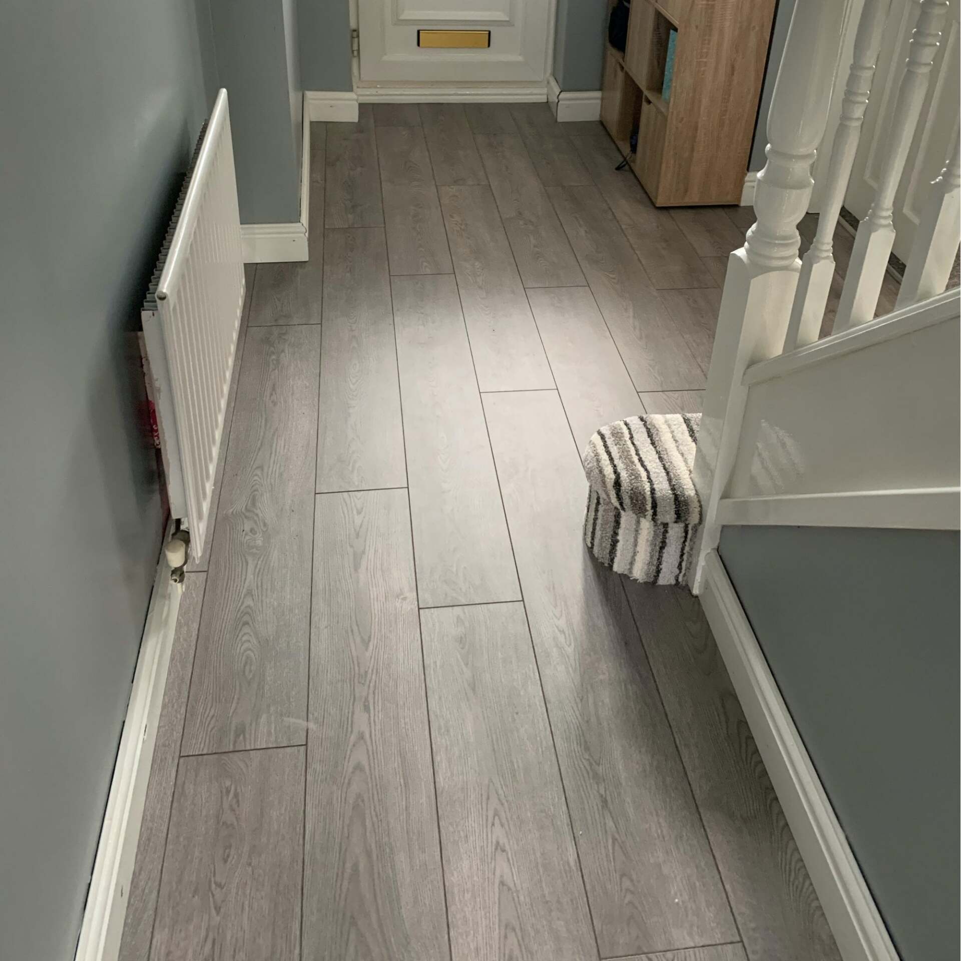 A hallway with hardwood floors and stairs in a house.