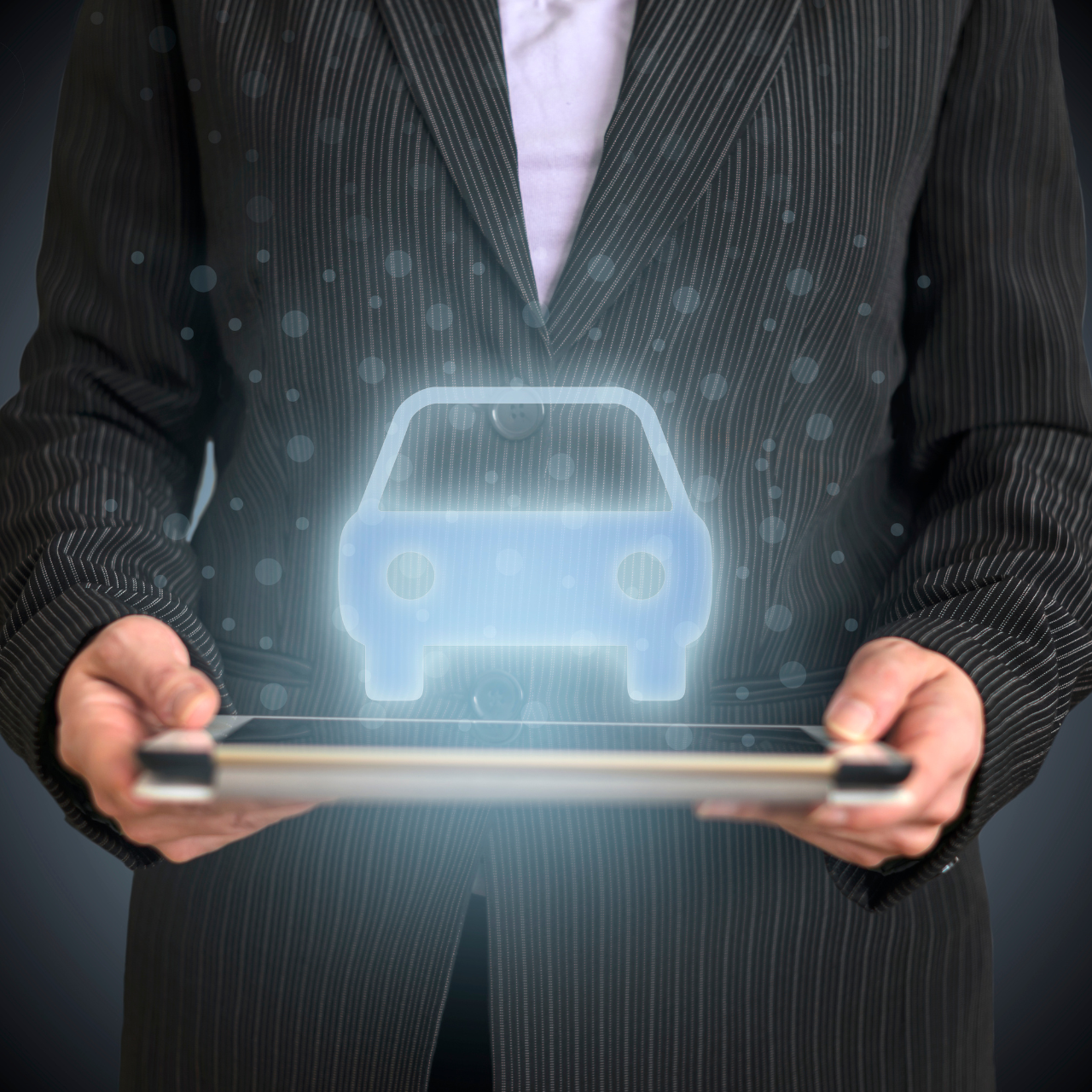Businessperson holding a tablet with a glowing blue car icon hovering above it