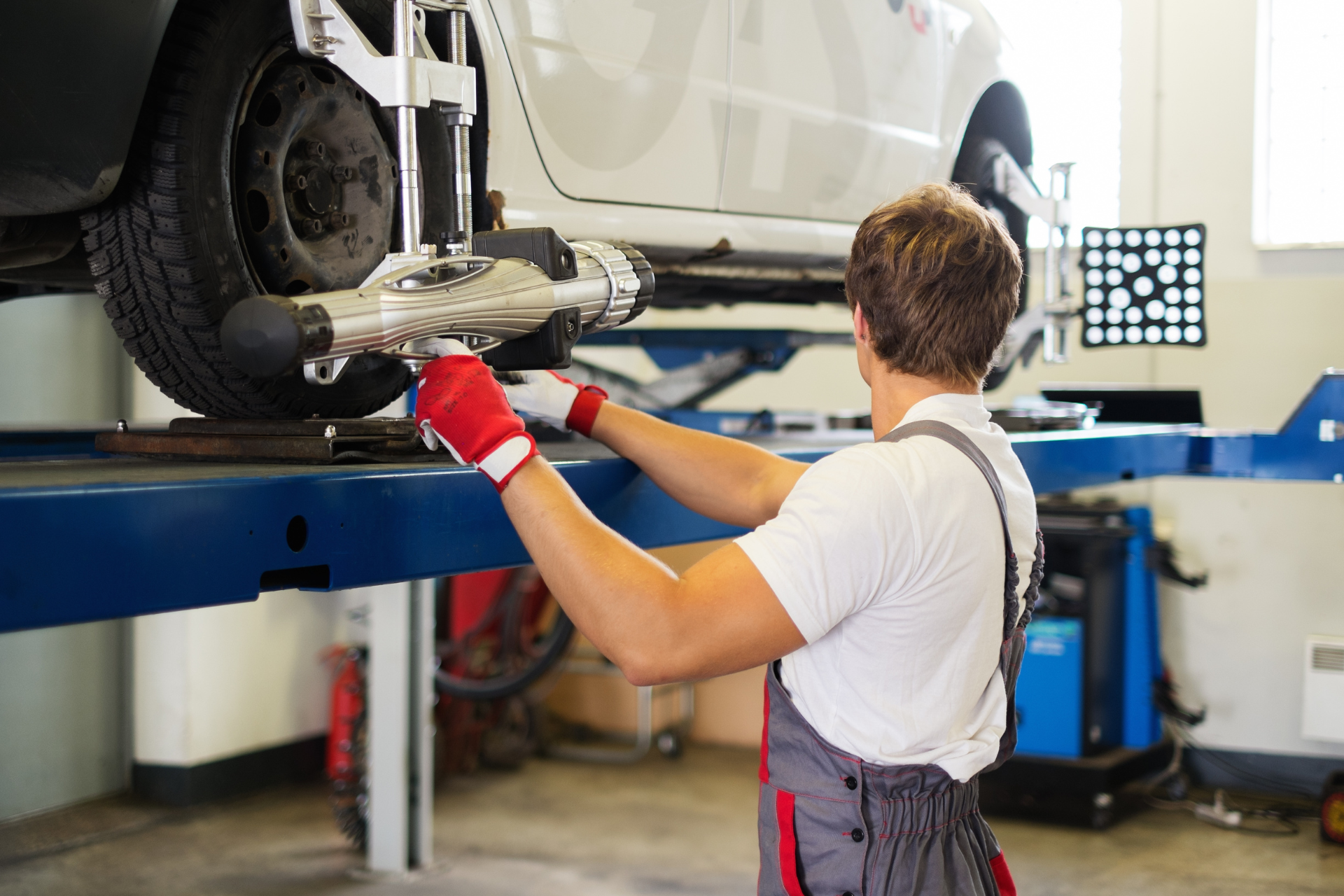 A man is working on a car on a lift in a garage.