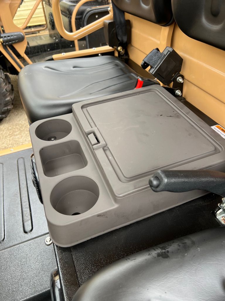 A dark gray storage console with two cup holders and a lidded compartment, positioned between vehicle seats.