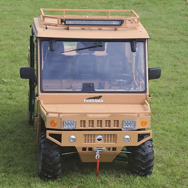A tan Tuatara UTV with a roof rack, light bar, and winch, parked on a grassy field, viewed from the front.