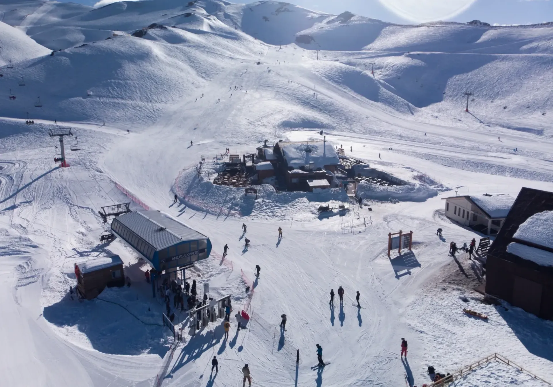 Ski resort with snowy slopes, ski lifts, and people gathered near lodge buildings