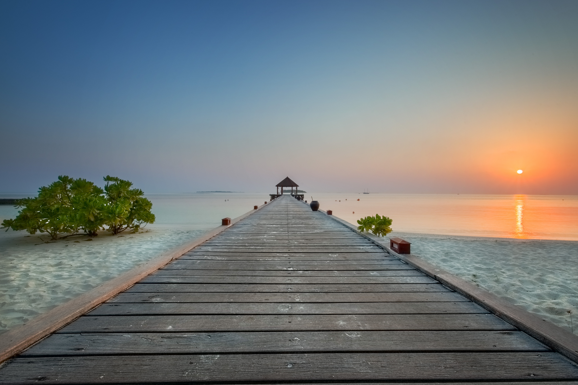A wooden pier leading to the ocean at sunset.
