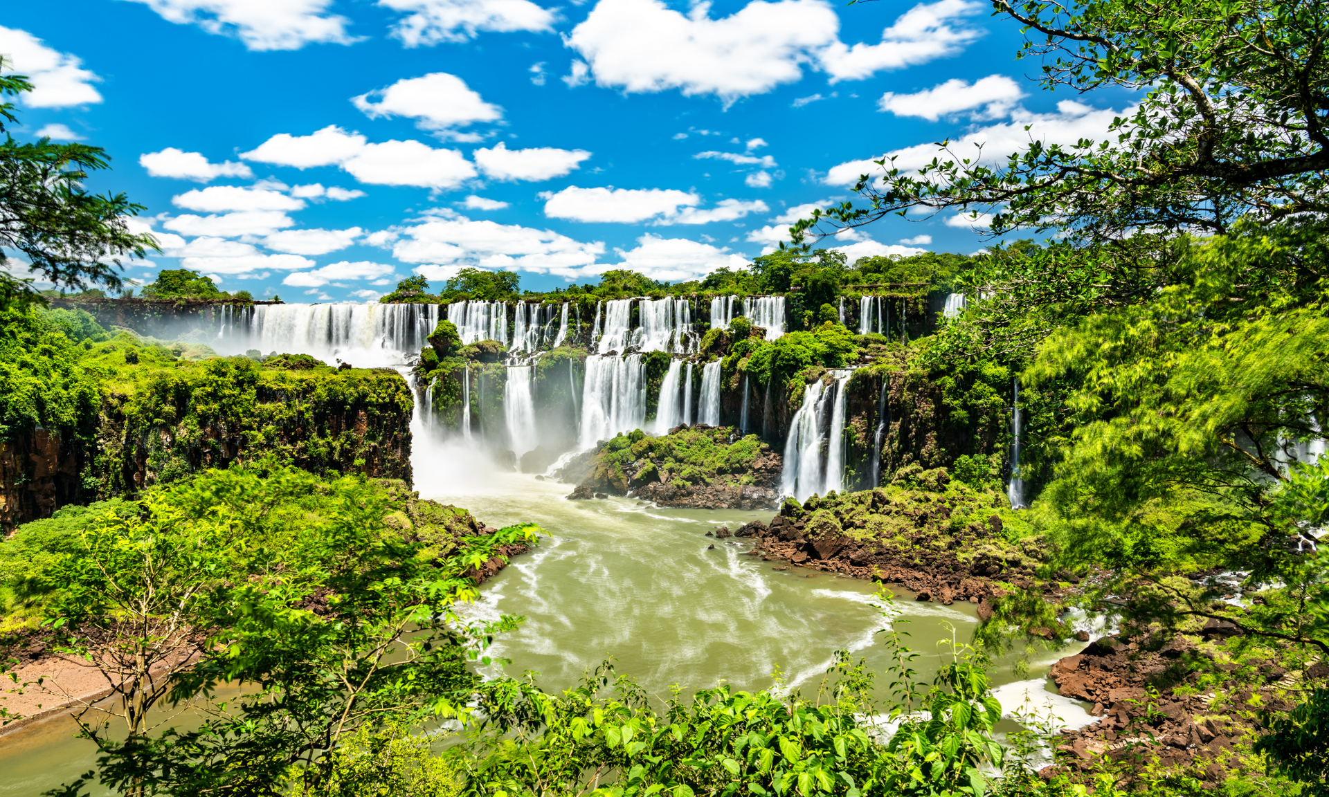 A waterfall is surrounded by trees and a river.