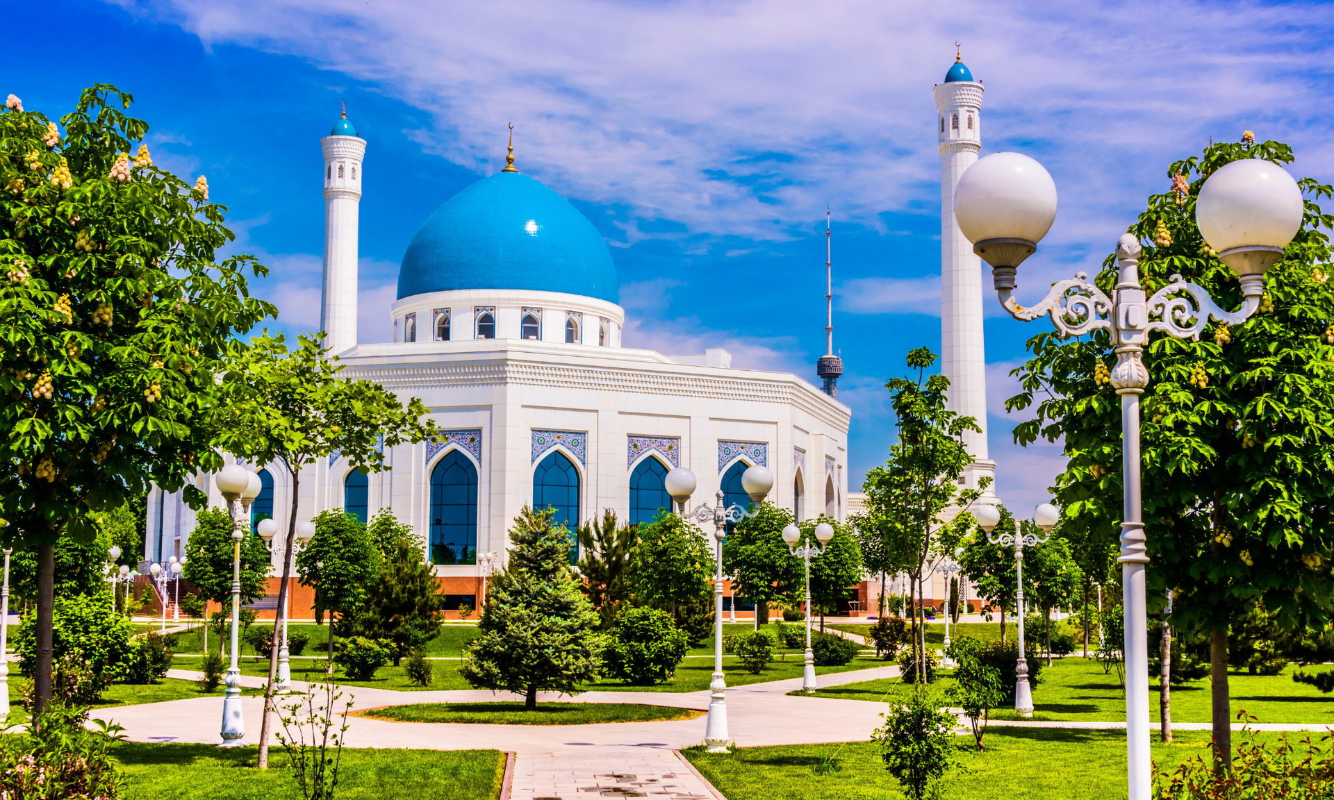 There is a mosque with a blue dome in the middle of a park in uzbekistan.