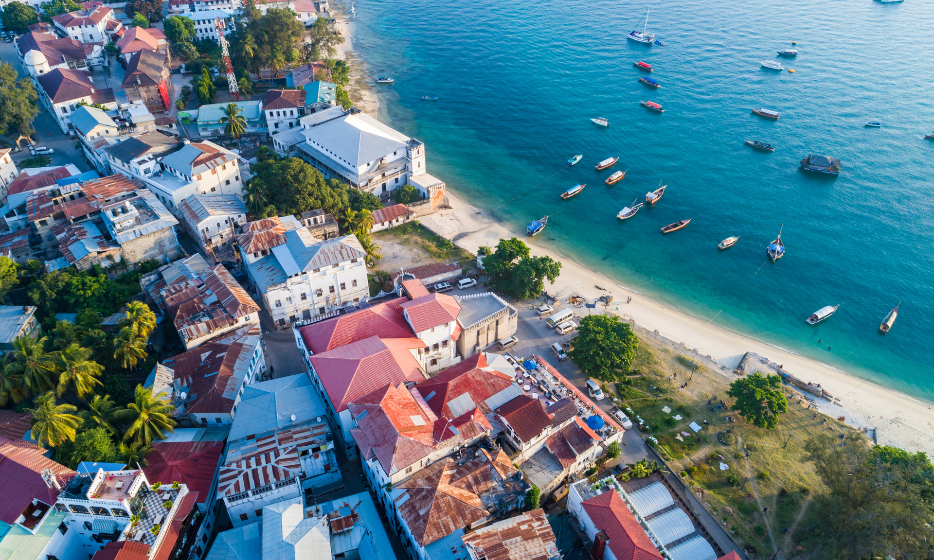 An aerial view of a city and a beach with boats in the water.