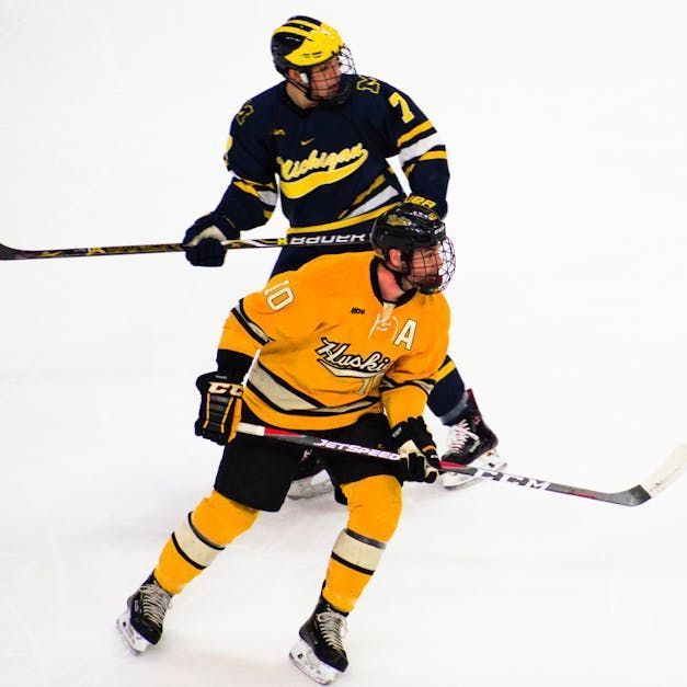 A hockey player wearing a yellow jersey with the letter a on it