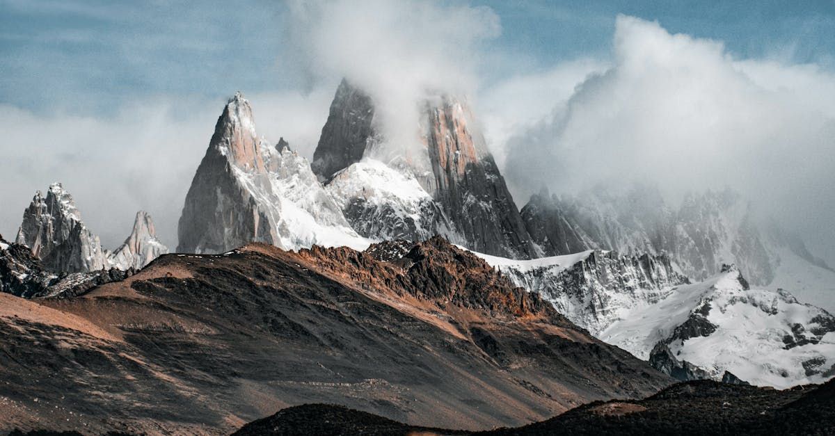 A mountain covered in snow and clouds with a blue sky in the background.