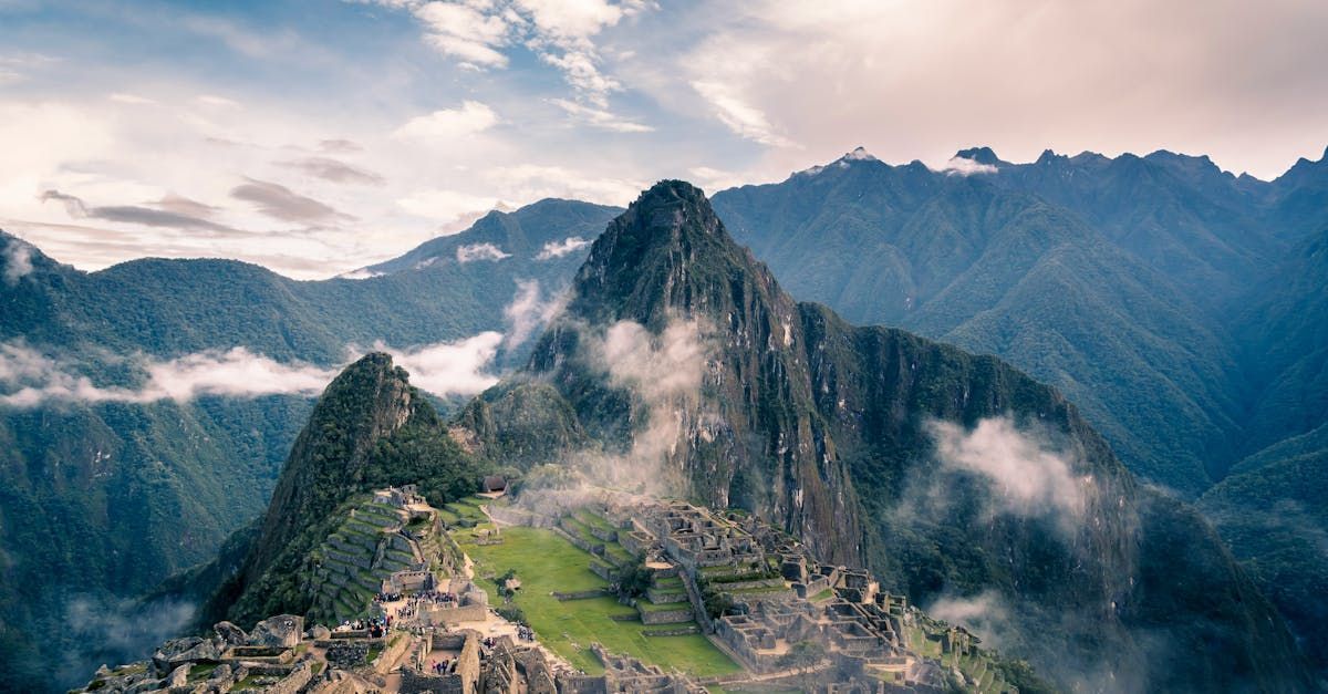 A mountain covered in clouds with a ruined city in the distance.