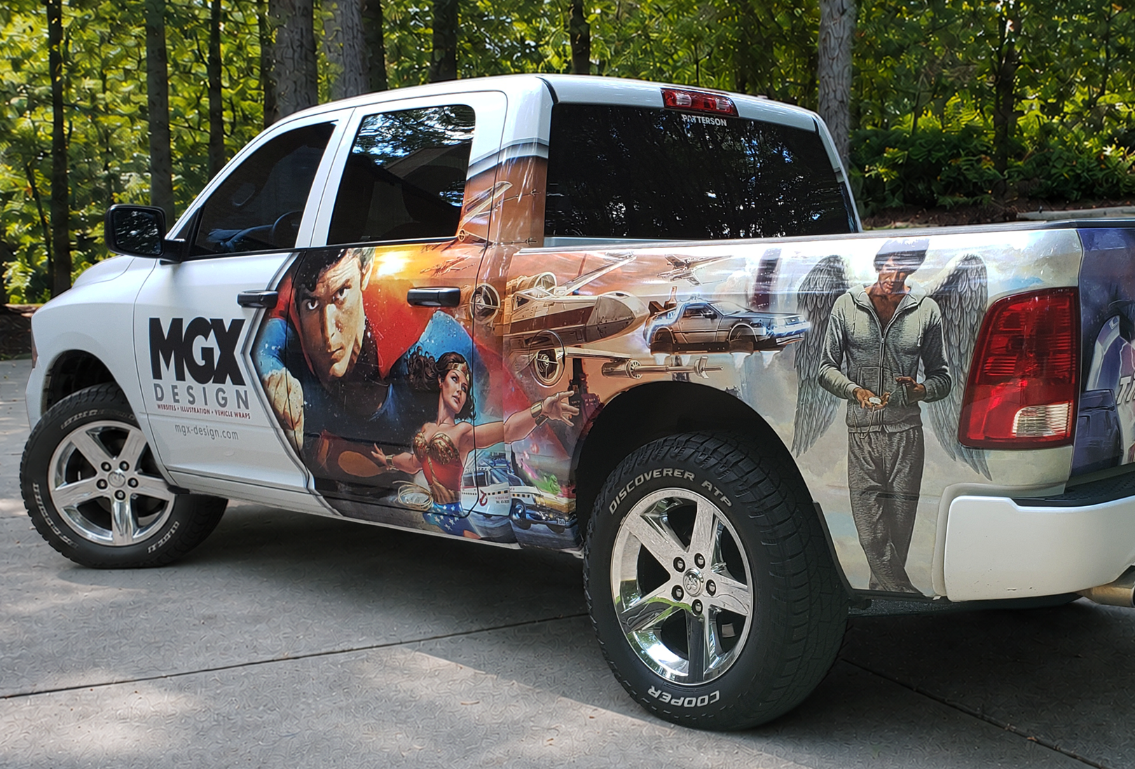 White pickup truck with colorful graphic wrap parked on a road beside trees