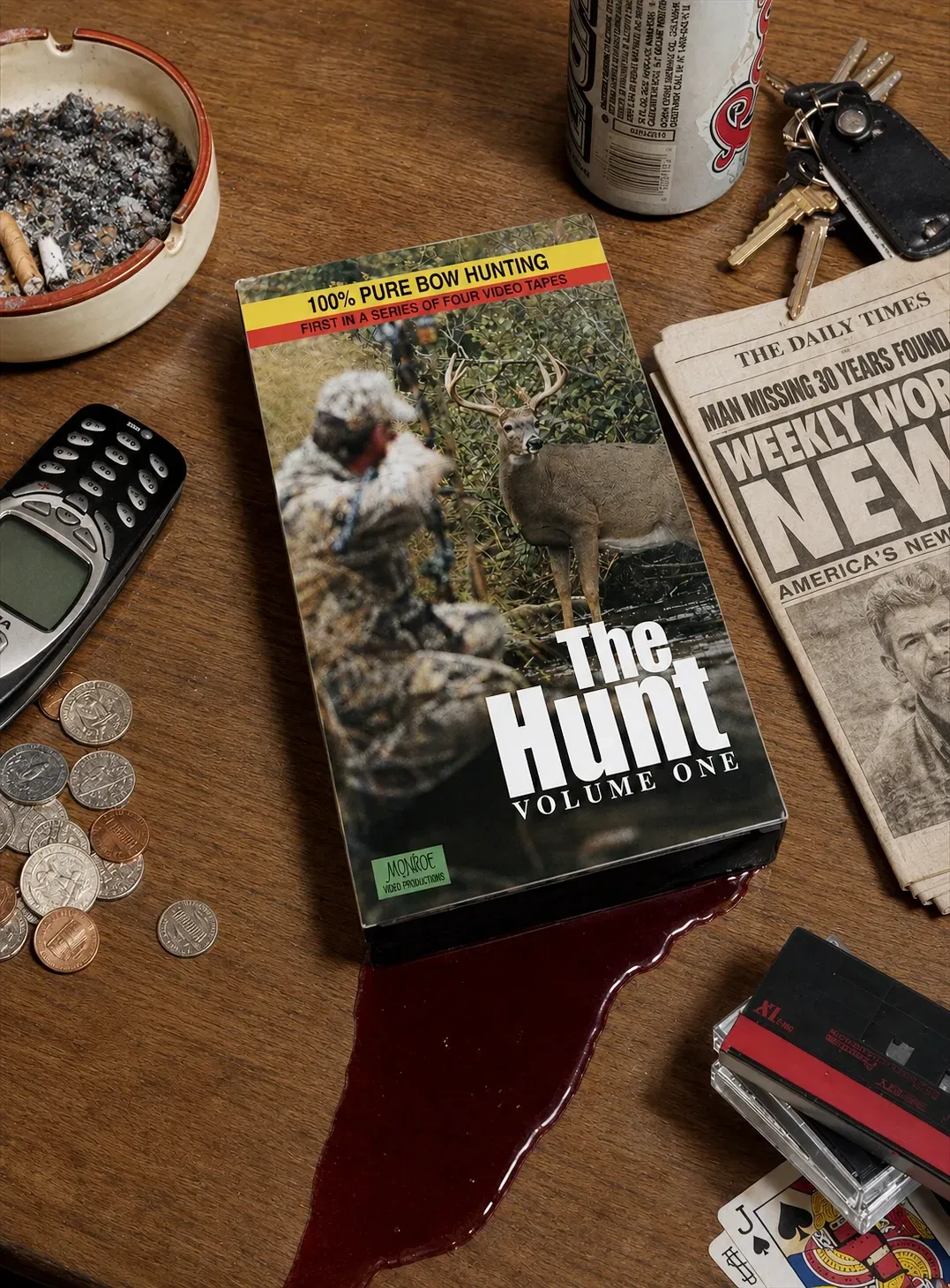 Hunting magazine on a wooden table with spilled red liquid, coins, a phone, ashtray, and keys nearby