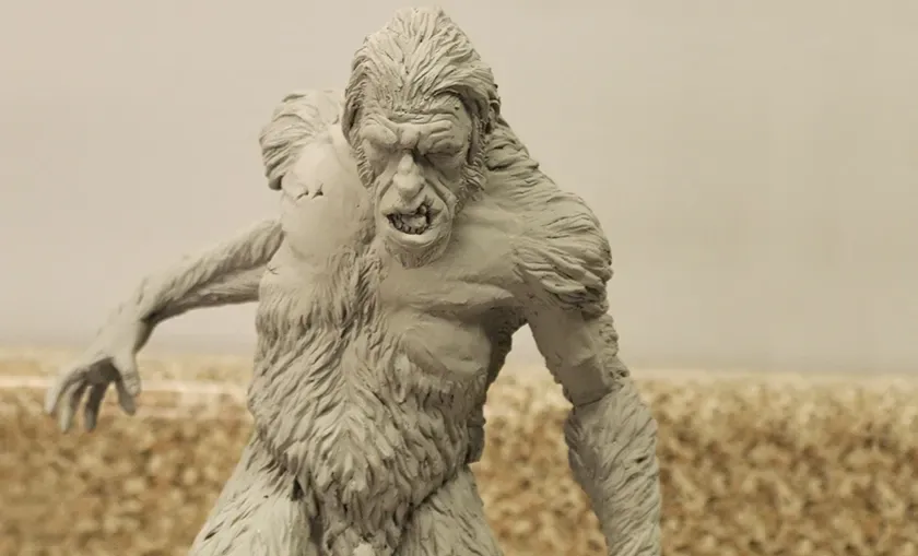 A snarling gray werewolf figurine with outstretched claws against a blurred beige background