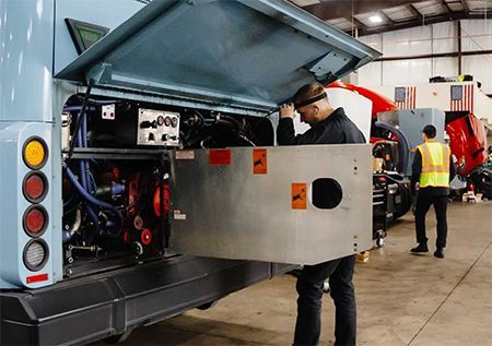Technician inspecting equipment inside an open utility truck in a workshop garage