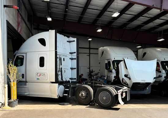 White semi-truck tractors parked inside a warehouse garage