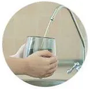 Hand filling a glass with water from a chrome faucet at a sink mirror
